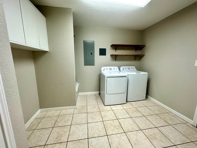 laundry area featuring cabinets, independent washer and dryer, electric panel, and light tile patterned flooring