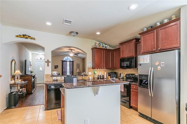 kitchen featuring vaulted ceiling, a breakfast bar, black appliances, light tile patterned floors, and kitchen peninsula