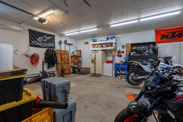 garage with a garage door opener, a baseboard radiator, white fridge with ice dispenser, and a workshop area