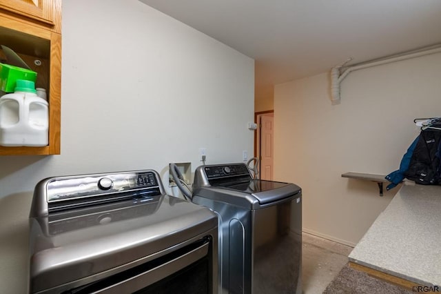 clothes washing area with cabinets and washer and clothes dryer