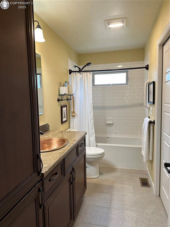 601 Petroleum Ave, Florence, CO 81226 - bathroom featuring vanity, toilet, shower / bath combination with curtain, and a textured ceiling