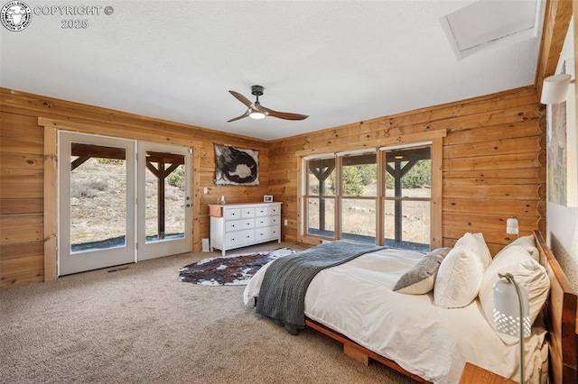 bedroom with attic access, carpet flooring, access to exterior, and wood walls