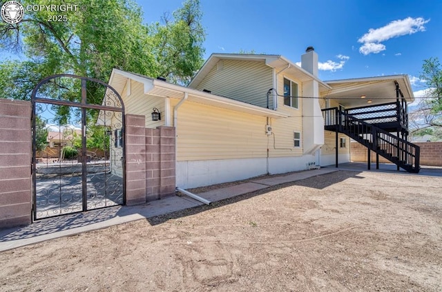 4401 Saint Clair Ave, Pueblo, CO 81005 - view of side of home with stairway, a gate, and a chimney