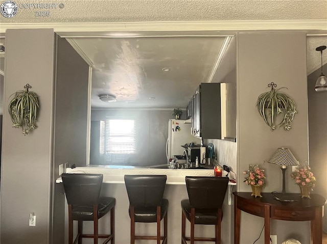 kitchen with sink, crown molding, a breakfast bar, and white refrigerator