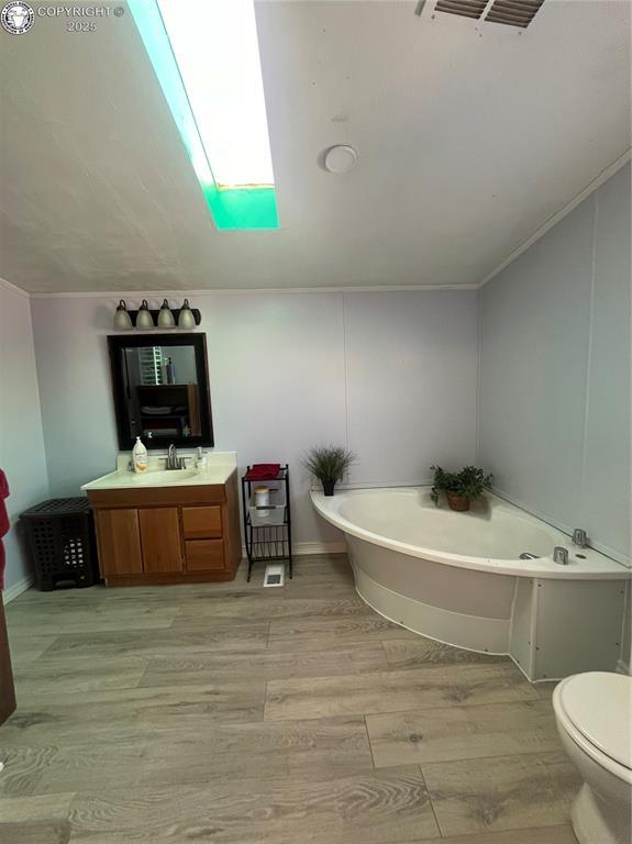 bathroom featuring vanity, a bath, hardwood / wood-style flooring, and toilet