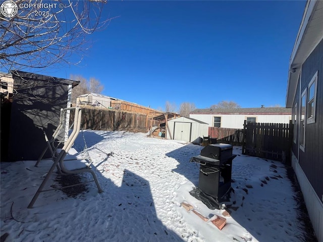 snowy yard featuring a shed