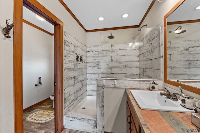 bathroom with hardwood / wood-style floors, a tile shower, vanity, ornamental molding, and toilet