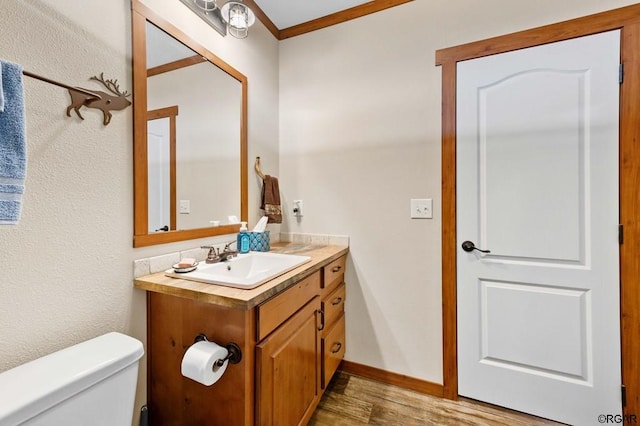 bathroom featuring vanity, crown molding, wood-type flooring, and toilet