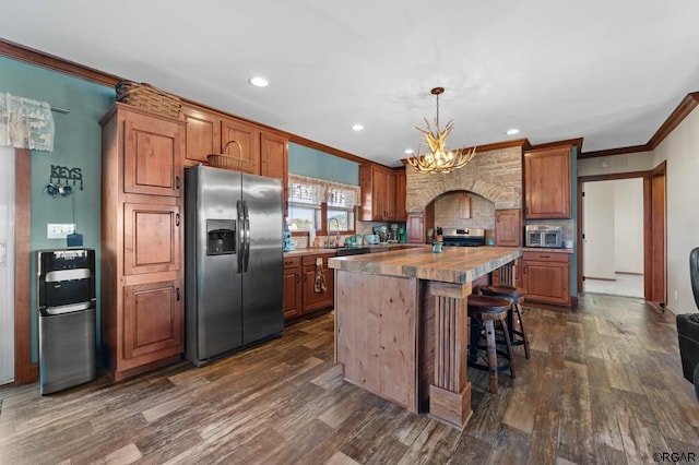 kitchen with dark hardwood / wood-style floors, decorative light fixtures, a center island, stainless steel appliances, and crown molding