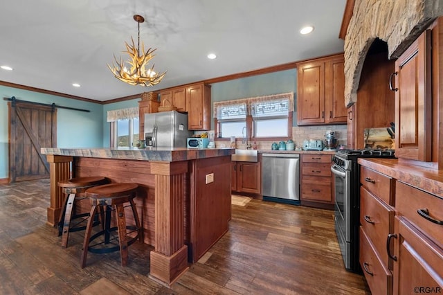 kitchen featuring a center island, appliances with stainless steel finishes, a kitchen breakfast bar, pendant lighting, and a barn door