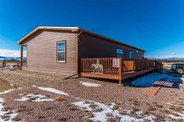 view of snow covered exterior featuring a deck with mountain view