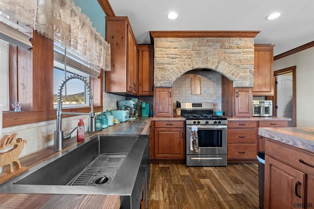 kitchen with sink, gas stove, crown molding, dark hardwood / wood-style flooring, and backsplash