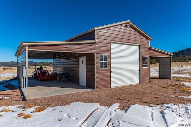 snow covered garage featuring a carport