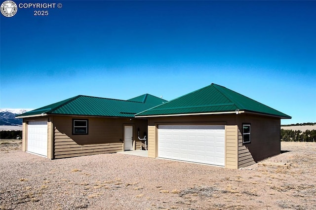 single story home featuring a garage, driveway, and metal roof