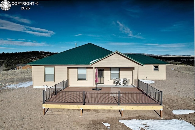 view of front facade with metal roof, a patio, and fence