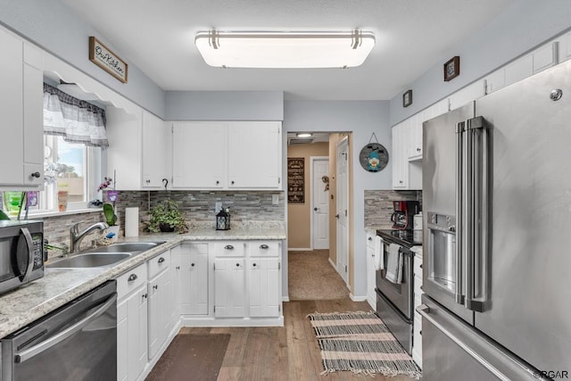 kitchen with dark wood-type flooring, sink, appliances with stainless steel finishes, white cabinets, and backsplash