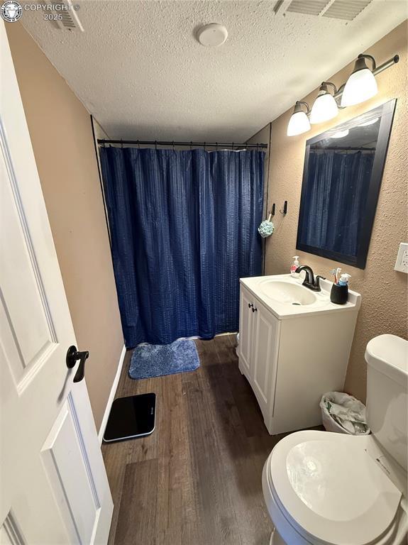 bathroom with hardwood / wood-style flooring, vanity, a textured ceiling, and toilet