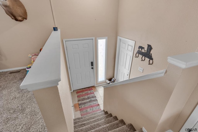 carpeted entrance foyer featuring a towering ceiling