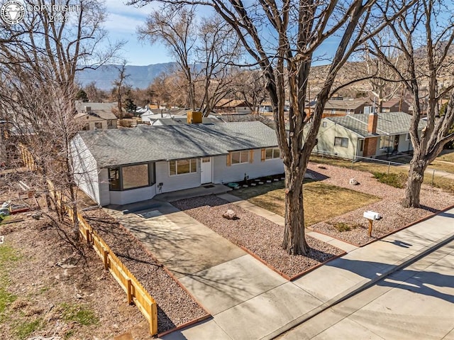 single story home featuring concrete driveway, a mountain view, a residential view, and a shingled roof