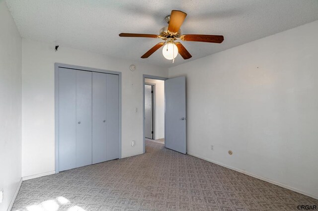 unfurnished bedroom featuring light carpet, a closet, and ceiling fan