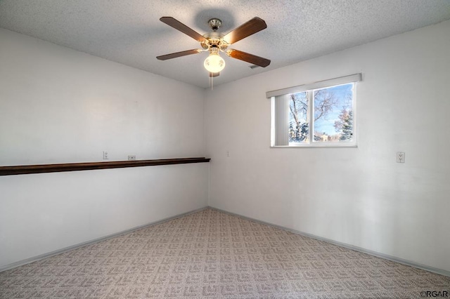 empty room featuring ceiling fan, light colored carpet, and a textured ceiling