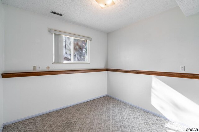 empty room featuring light carpet and a textured ceiling