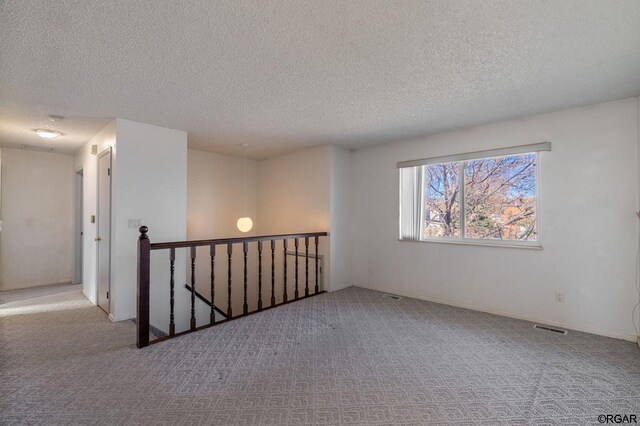 unfurnished room featuring light colored carpet and a textured ceiling