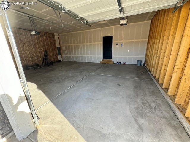 garage with a garage door opener and wooden walls