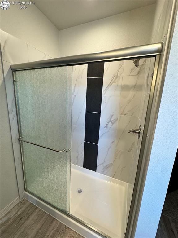 bathroom featuring a shower with shower door and hardwood / wood-style floors