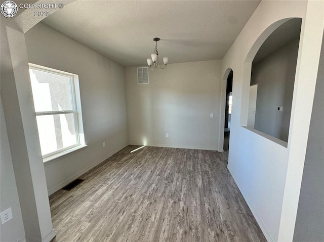 unfurnished dining area featuring an inviting chandelier and hardwood / wood-style flooring