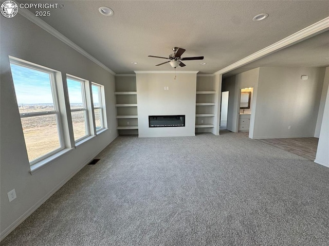 unfurnished living room with built in shelves, crown molding, a textured ceiling, carpet flooring, and ceiling fan