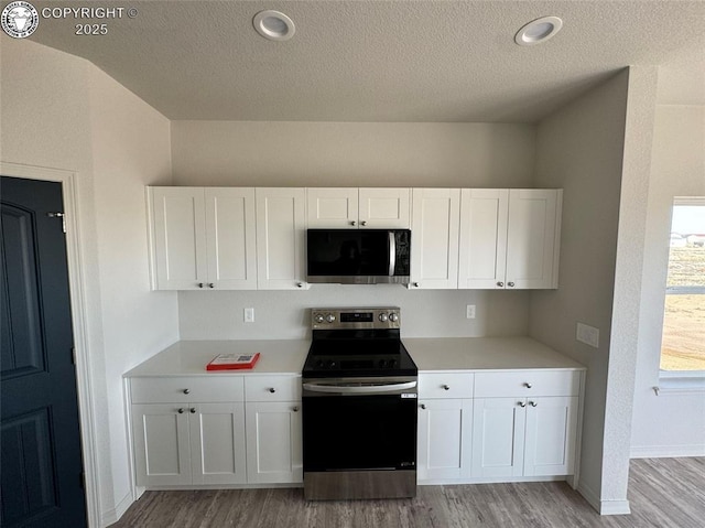 kitchen featuring white cabinetry, light hardwood / wood-style flooring, stainless steel appliances, and a textured ceiling