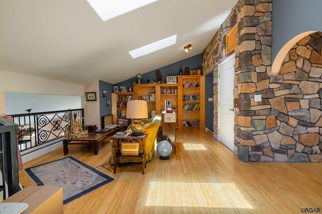 sitting room featuring lofted ceiling with skylight and light wood-type flooring