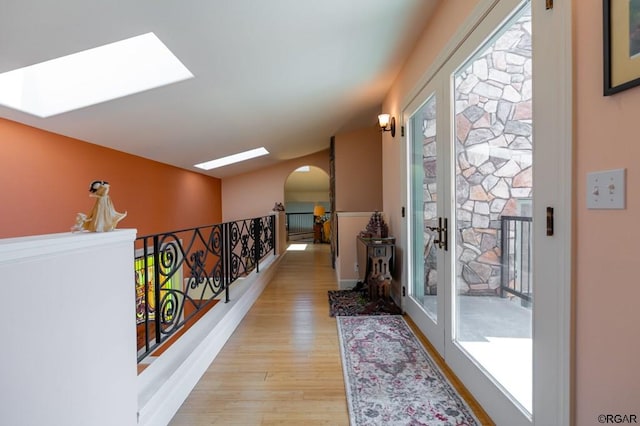 corridor featuring light wood-type flooring and a skylight