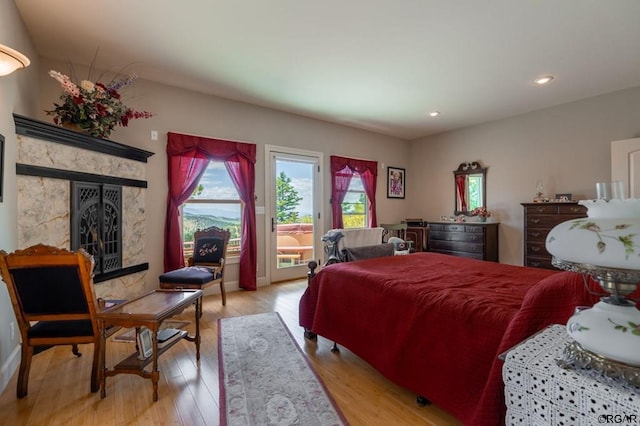 bedroom with a tiled fireplace and light hardwood / wood-style flooring