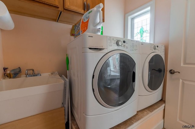 clothes washing area featuring cabinets, sink, and washing machine and dryer