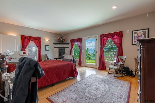 bedroom featuring access to exterior, a fireplace, and light wood-type flooring