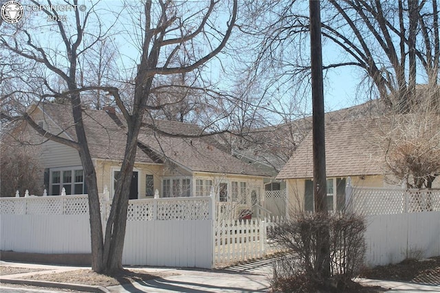 view of front facade with a fenced front yard and roof with shingles