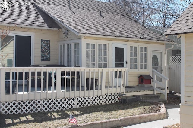 exterior space with a deck and roof with shingles