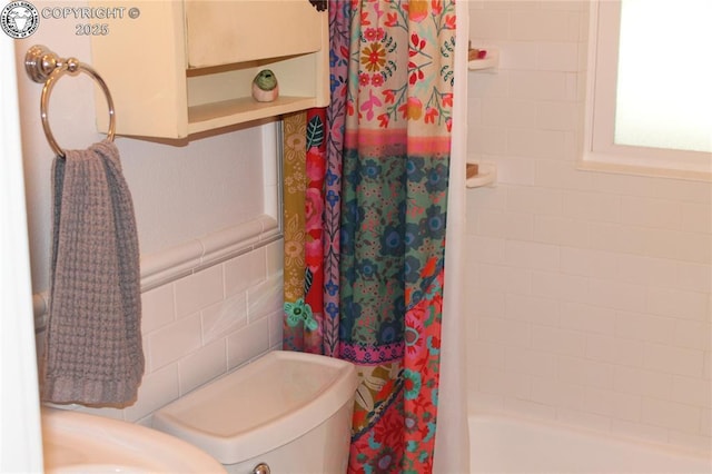 full bath featuring shower / bath combo, wainscoting, and tile walls