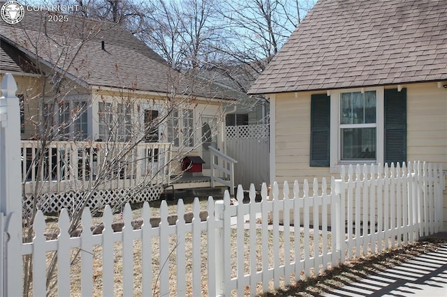 exterior space featuring a fenced front yard and roof with shingles