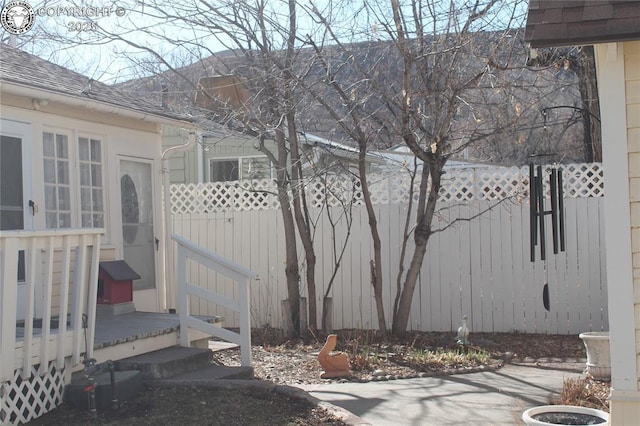 exterior space with fence, a deck, and roof with shingles