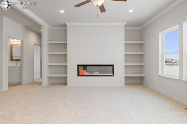 unfurnished living room with ornamental molding, a glass covered fireplace, and built in features