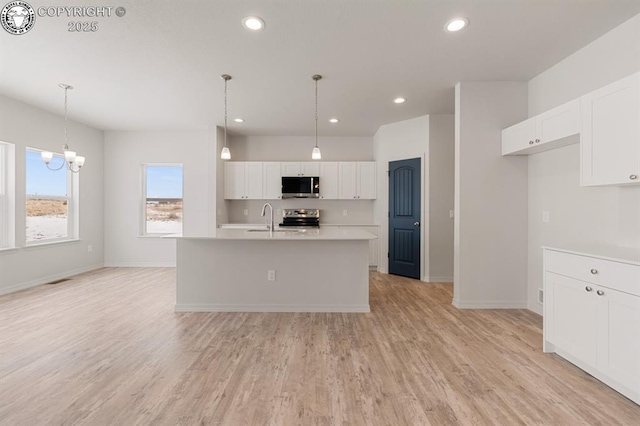 kitchen featuring light wood-type flooring, white cabinets, stainless steel appliances, and light countertops