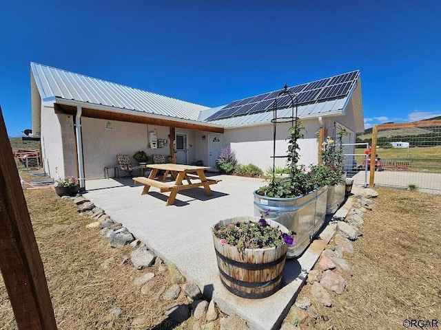 back of property with a patio and solar panels