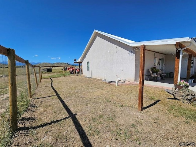 view of property exterior with a patio and a lawn