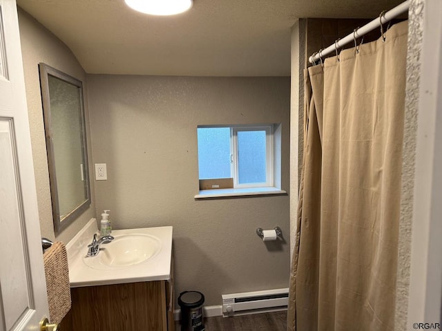 bathroom with vanity, a baseboard heating unit, hardwood / wood-style flooring, and walk in shower