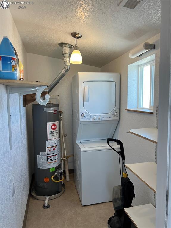 5105 Electric Ave, Westcliffe, CO 81252 - laundry area featuring gas water heater, stacked washing machine and dryer, a textured ceiling, and light carpet