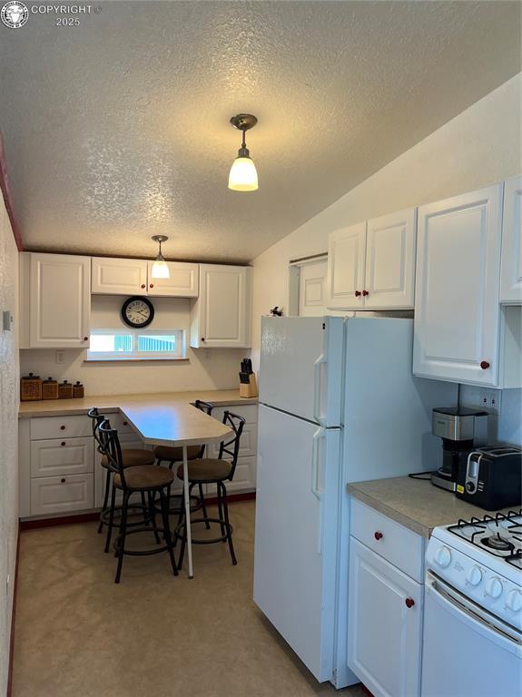 5105 Electric Ave, Westcliffe, CO 81252 - kitchen featuring white cabinetry, white appliances, a textured ceiling, lofted ceiling, and light countertops