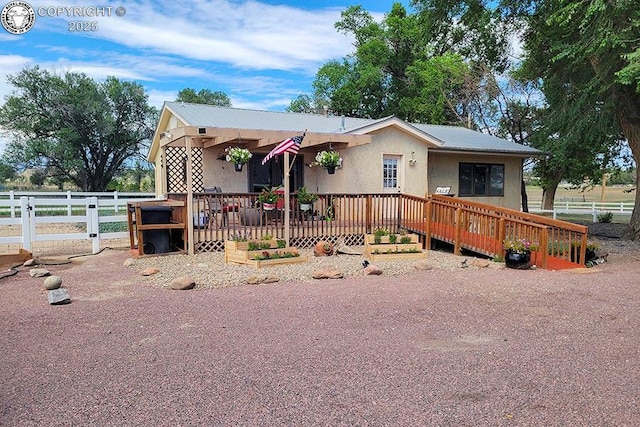 view of front facade with a deck, fence, and stucco siding